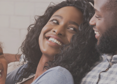 Homem e mulher sorrindo um para o outro com uma criança