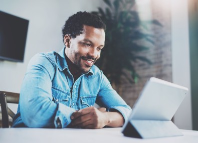 Homem sorrindo e olhando para tablet