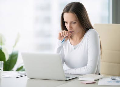 Mulher com caneta olhando computador