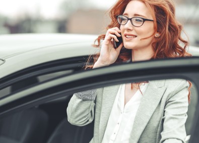 Mulher falando no celular e entrando no carro