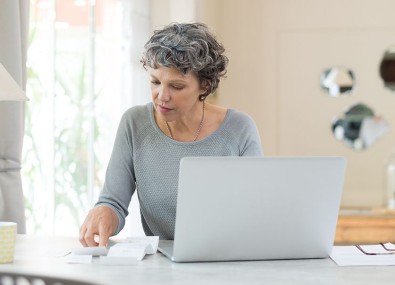 Mulher mexendo no computador e olhando papéis