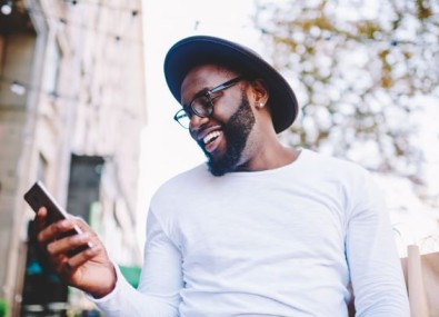 Homem sorrindo mexendo no celular