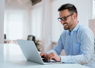 Homem sorrindo mexendo no computador