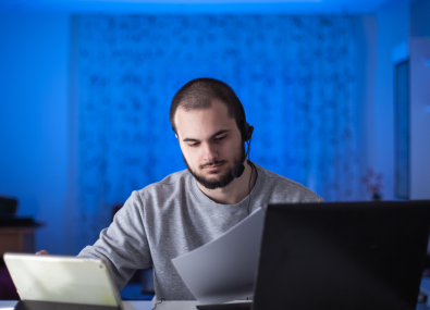 Homem com fone de ouvido usando computador e tablet